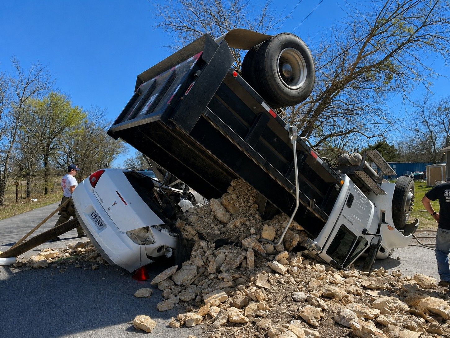 Crews work a dump-truck rollover onto a passenger car