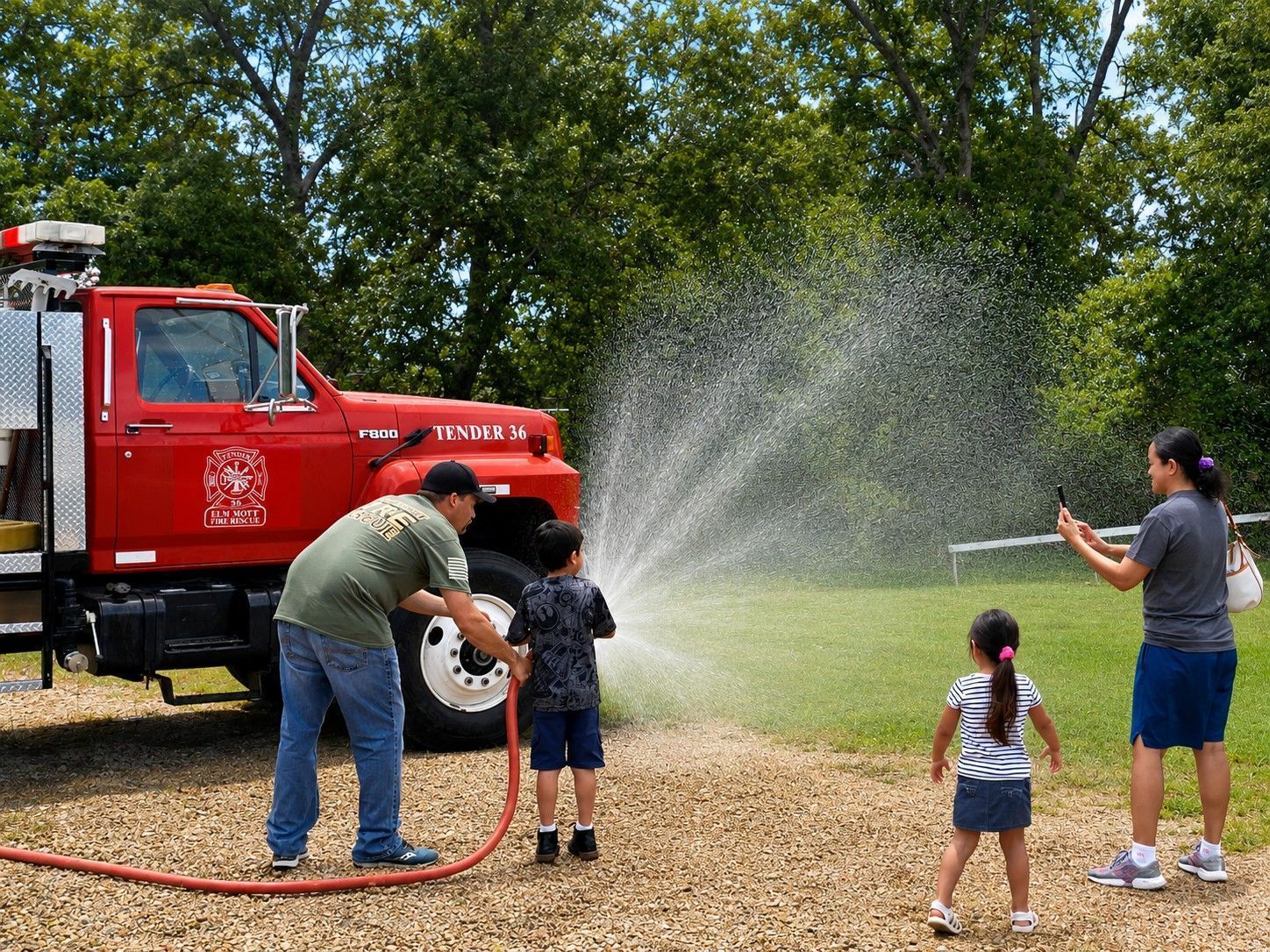 A child sprays a hose line off Tender 36 as family watches
