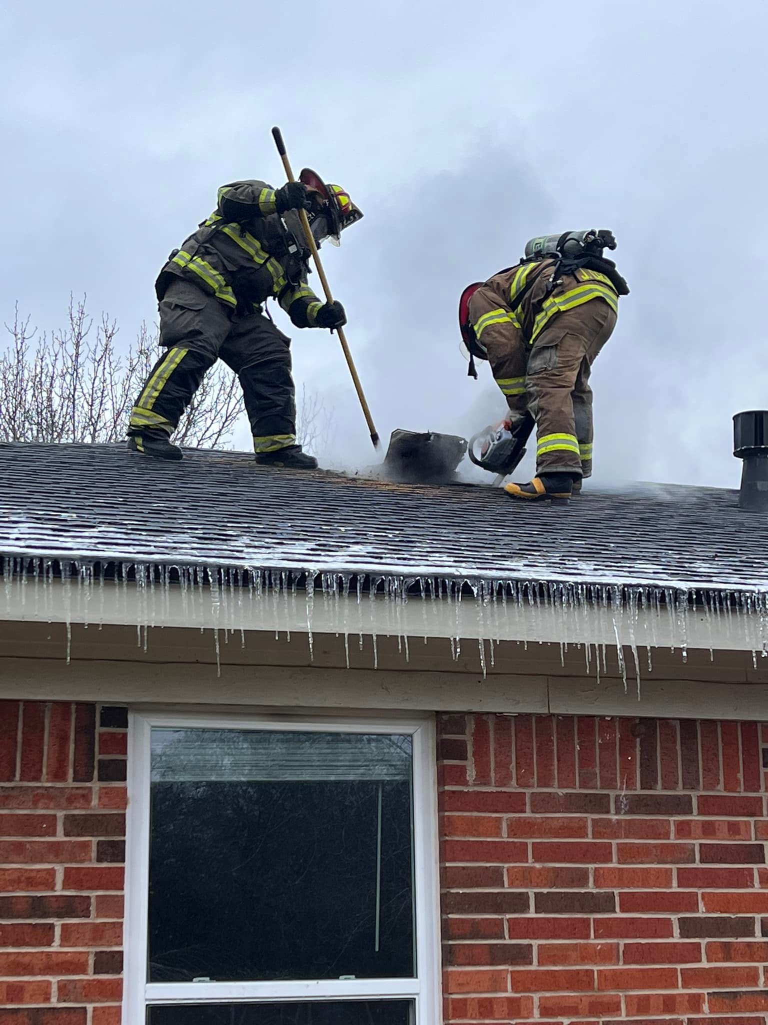 Firefighters cut a ventilation hole on an icy roof