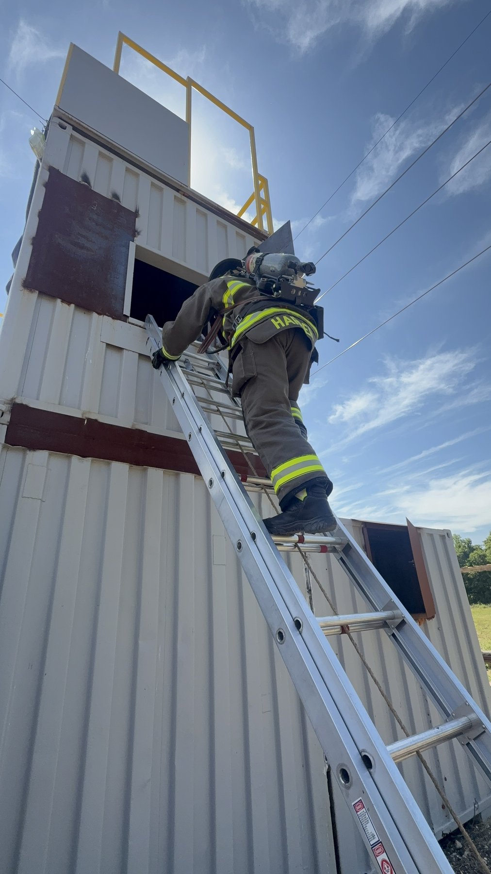 An Elm Mott firefighter climbing a ground ladder to a tower window during training